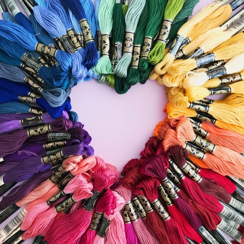 Rolls of colourful wool, organised by similar colours and leaving a heart shape in the middle