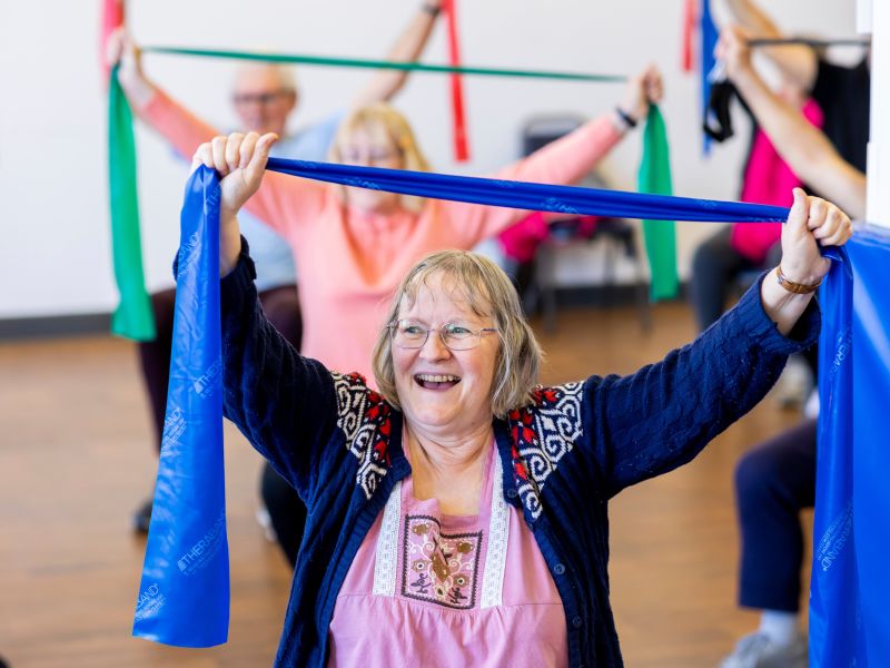 People in an exercise class holding colourful scarves