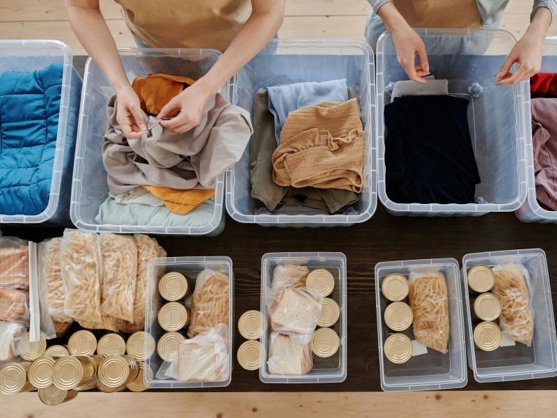 Photo of two volunteers preparing food and clothing boxes for a charity