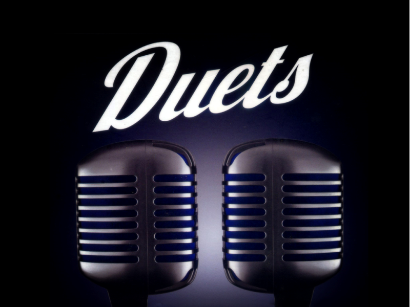 graphic showing two microphones with the word 'duets'