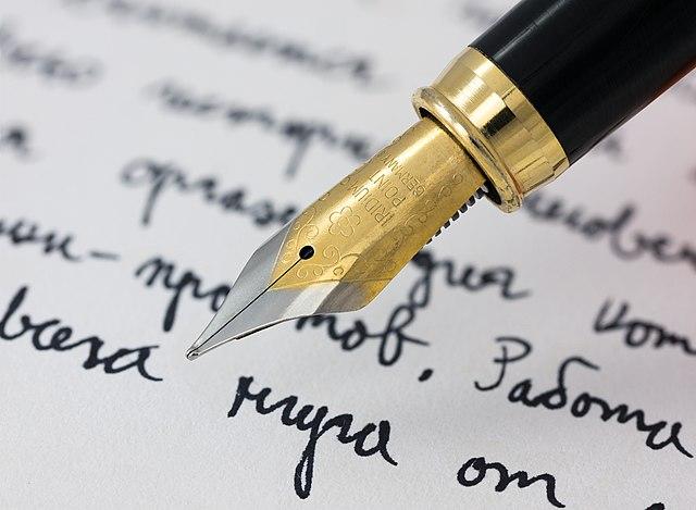 gold nib of fountain pen writings on white paper