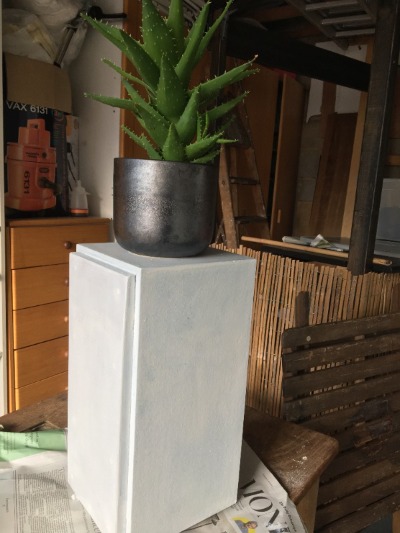 plant standing on a white plinth, plinth was once a speaker