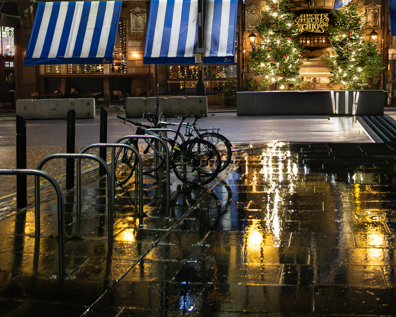 Photo of a wet square, shining with Christmas lights.