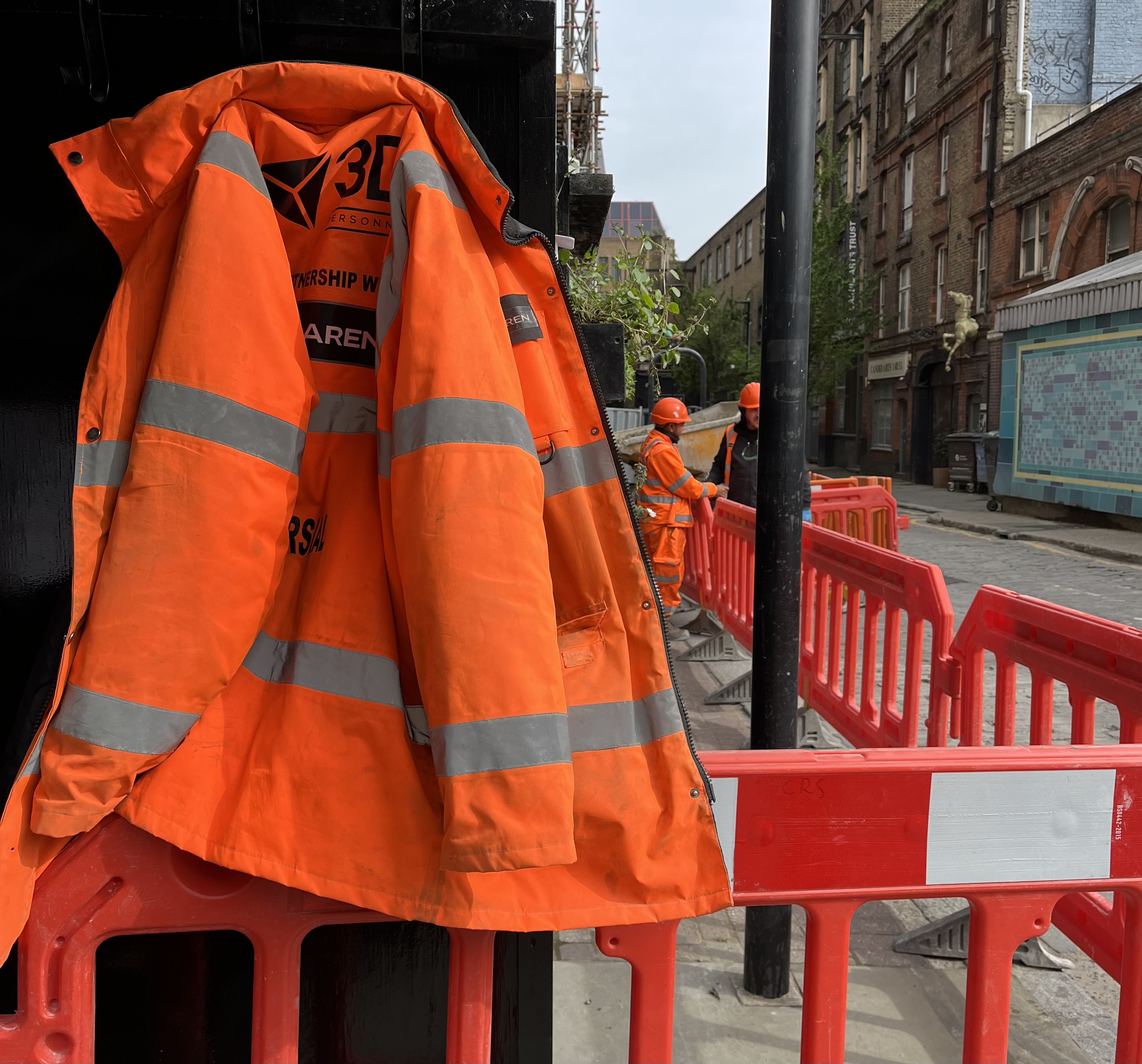 Photo of a workman's jacket and orange safety barriers