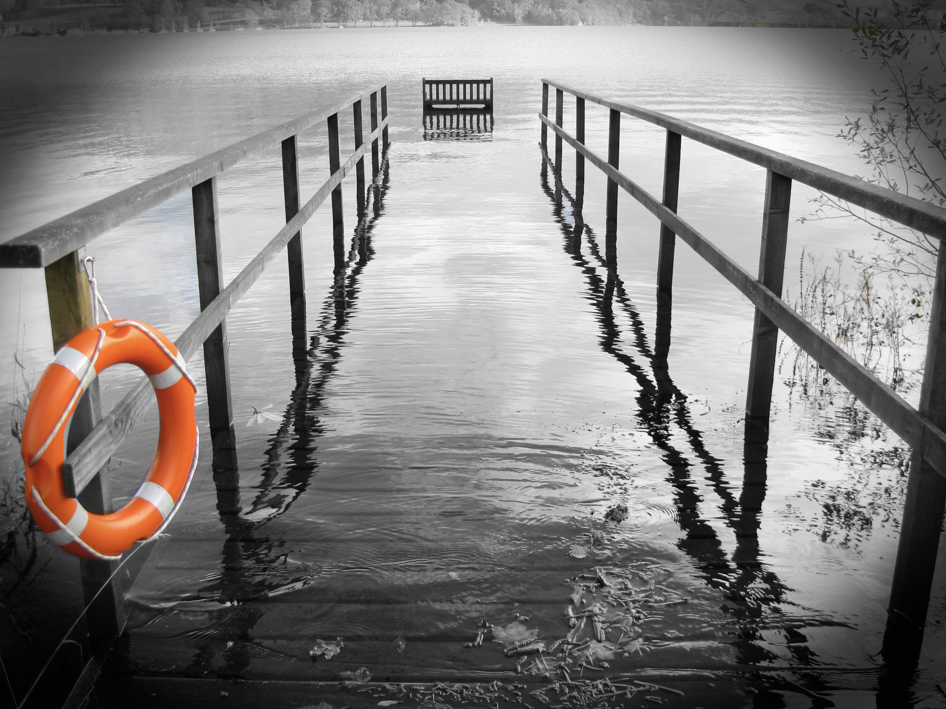 A photo a lake flooding over a jetty and a bright orange safety ring