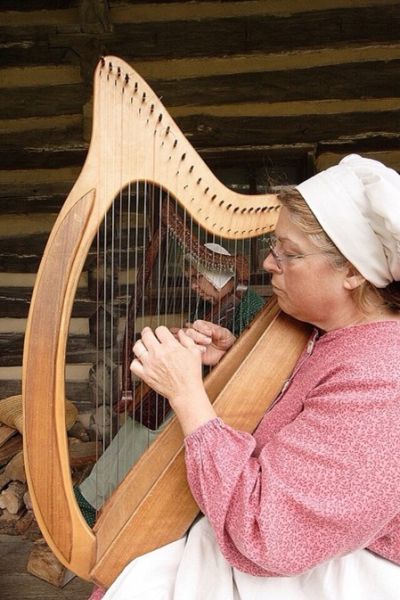 a woman playing a wooden harp 